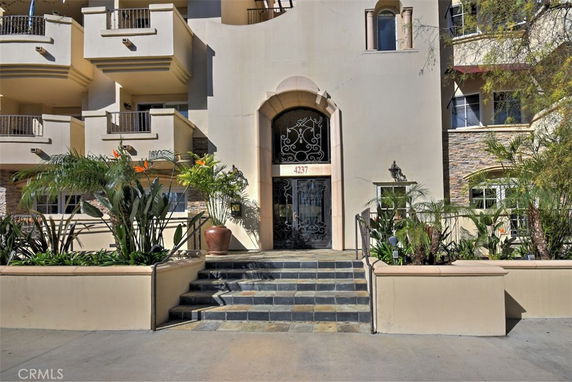 Front view of a multi-story building with balconies and a central entrance.