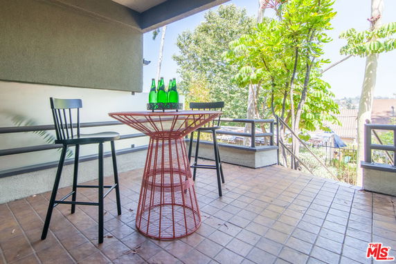 Patio area with tall chairs and a table overlooking surrounding trees and landscape
