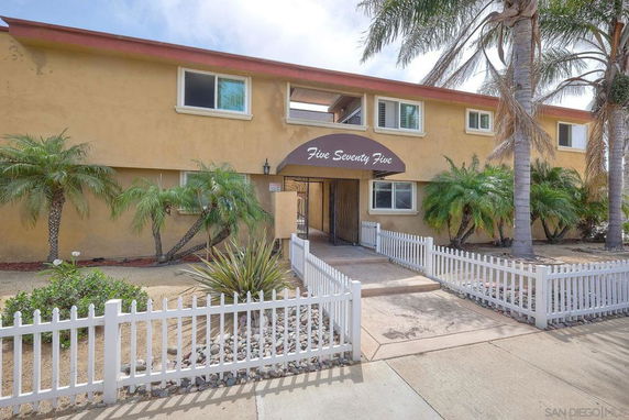 Front view of a two-story building with entrance canopy and surrounding palm trees.