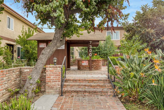 Front view of a building entrance with brick walkway and greenery.