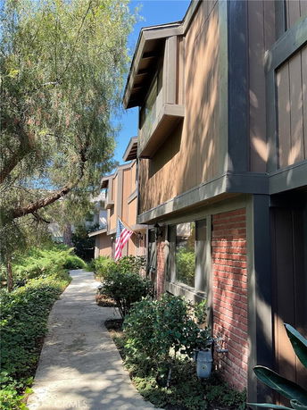 Side view of a multi-story townhouse with wooden and brick exterior.