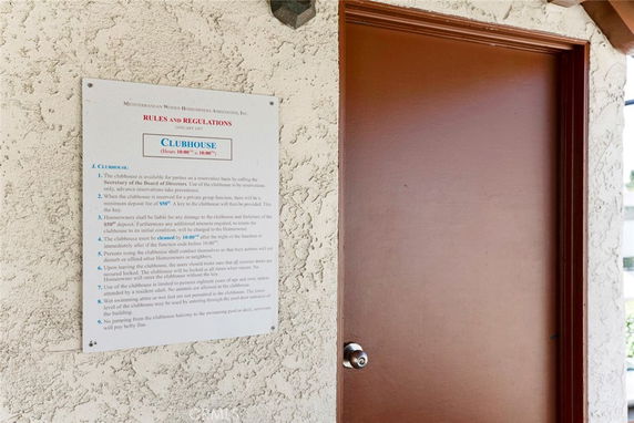 Entrance door to a clubhouse with rules and regulations sign on the wall.