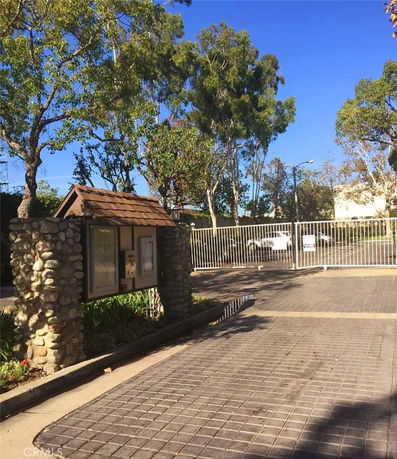 Gated outdoor parking area with a stone information board.