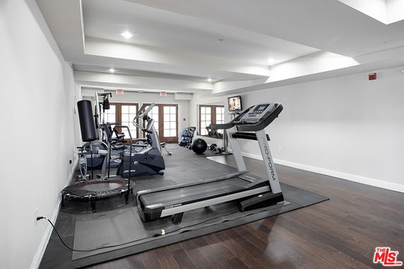 Indoor gym area with exercise equipment including a treadmill, elliptical machines, and a punching bag.