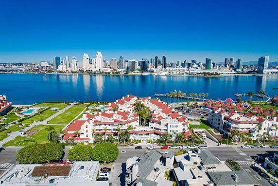 Skyline view of tall buildings across a body of water from a neighborhood with red-roofed houses.