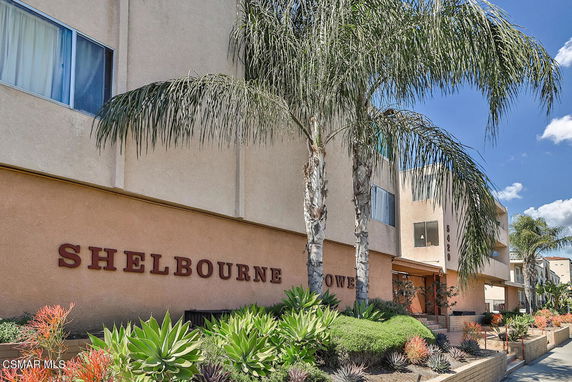 Front view of a multi-story apartment building with palm trees.
