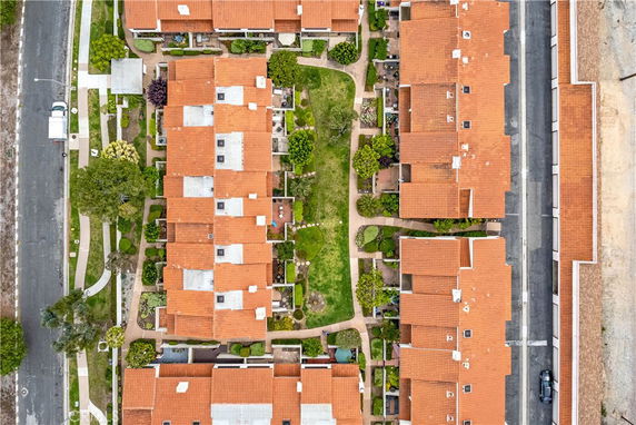 Aerial view of a residential area with multiple houses featuring red-tiled roofs and landscaped gardens.