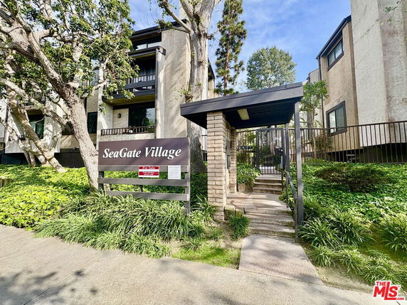 Front entrance view of SeaGate Village apartment complex with surrounding greenery.