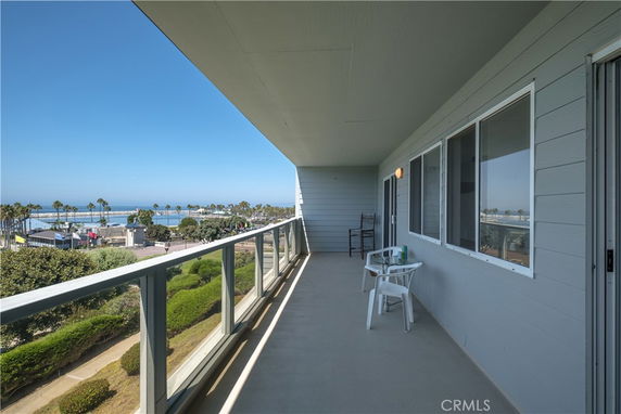 Balcony of a building overlooking a coastal area with ocean view and palm trees.