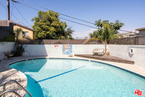 Outdoor swimming pool with surrounding fence and seating area.