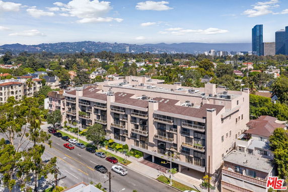 Front view of a multi-story building with balconies and a flat roof.