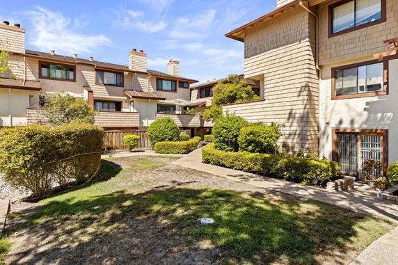 Front view of residential multi-story buildings with shingled roofs and multiple windows.