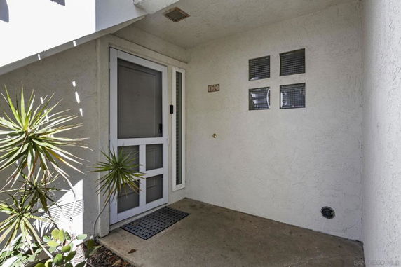Entrance view of a house with a white door and small windows beside it.