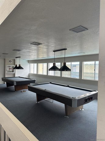 Interior of a recreational room with pool tables and lighting fixtures.