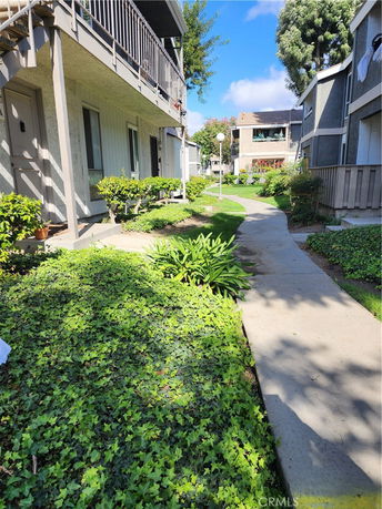 Exterior view of multi-story residential buildings with balconies and landscaped walkway.