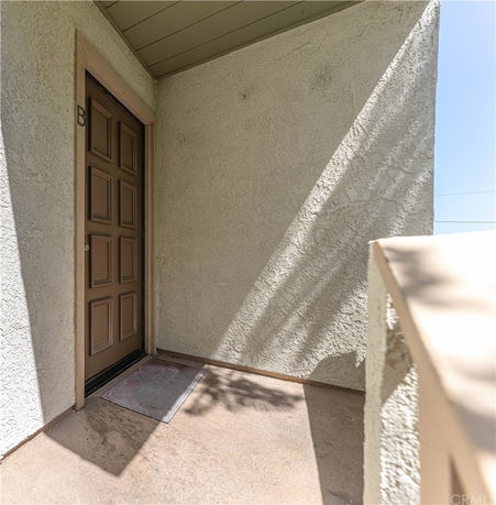 Exterior view of an entry door with textured stucco walls.