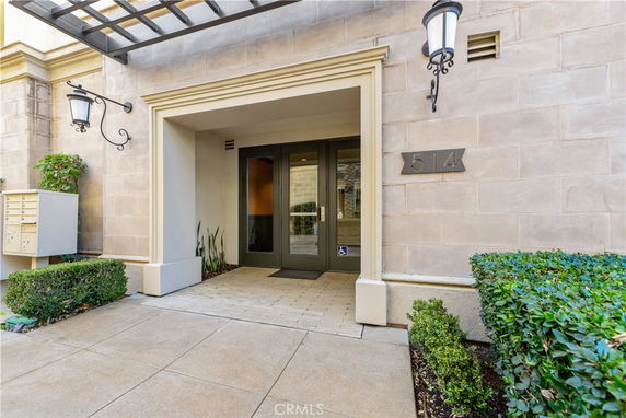 Entrance of a building with double glass doors and wall-mounted lanterns.