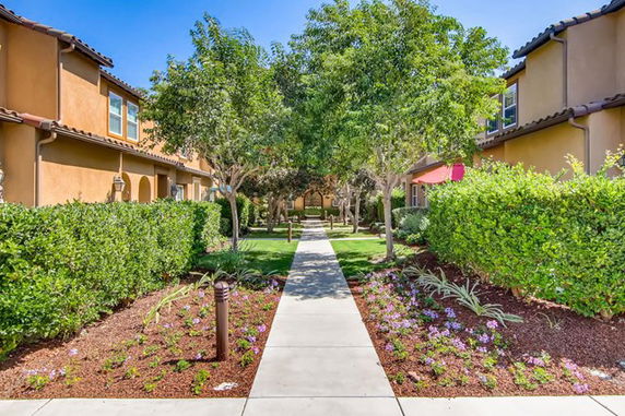 Front view of a two-story building with a walkway and gardens.