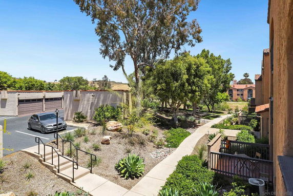 View from a building showing a landscaped garden area with pathways and garages in the background.