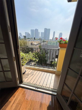 View of a city skyline from a balcony with potted plants and railing.