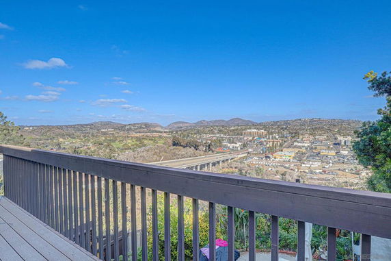 Panoramic view of a cityscape with mountains in the background and a railing in the foreground.