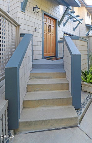 Front view of a house entrance with steps leading to a wooden door.