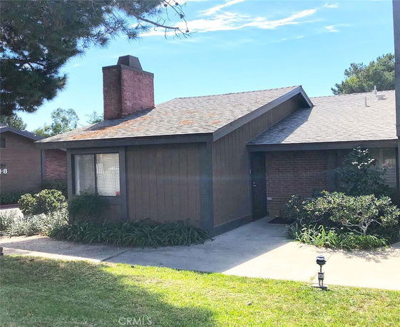 Front view of a single-story house with a chimney and a sloped roof.
