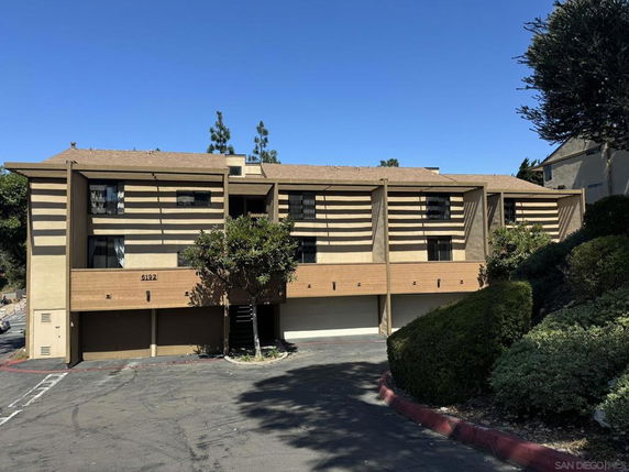 Front view of a multi-story building with garages on the ground level and balconies above.