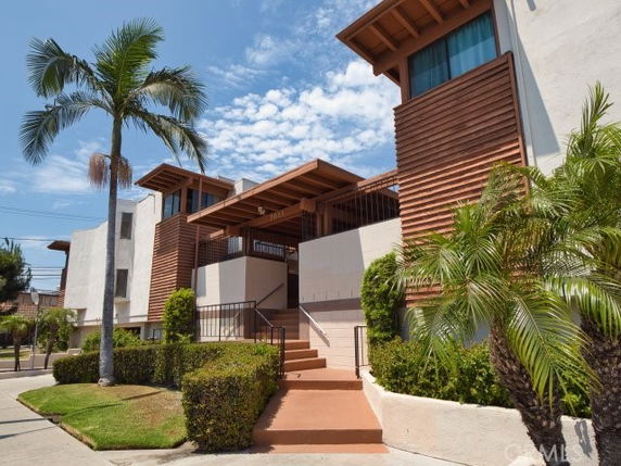 Front view of a modern multi-story building with wooden accents and a staircase entrance.
