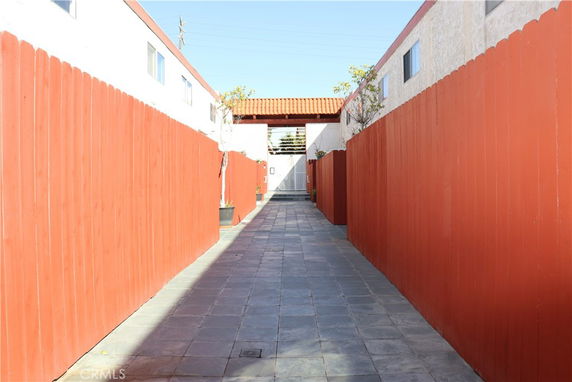 Narrow walkway between buildings with red fences.