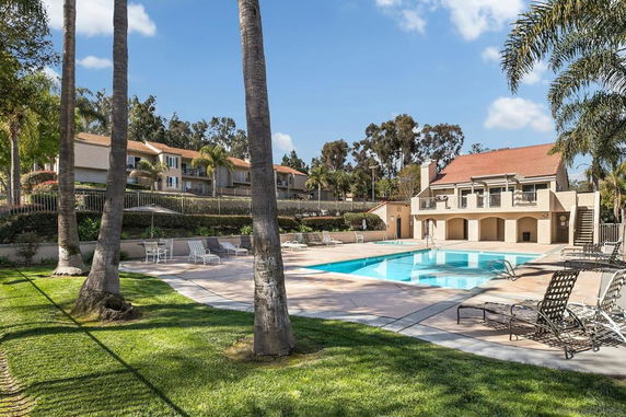 View of a swimming pool area with lounge chairs and a building in the background.