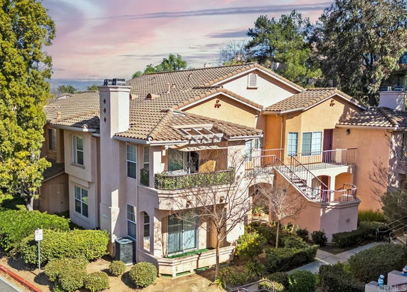 Front view of a multi-story residential building with balconies and a tiled roof.