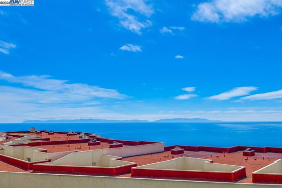 Panoramic view of a building's rooftop with a background of the ocean and distant landmasses.