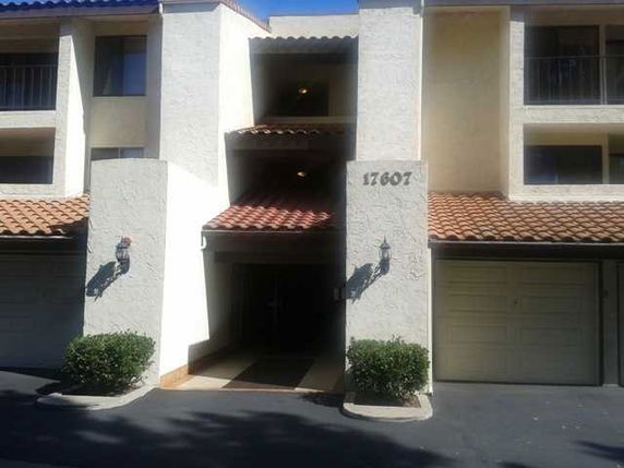 Front view of a multi-story building with balconies and a tiled roof.