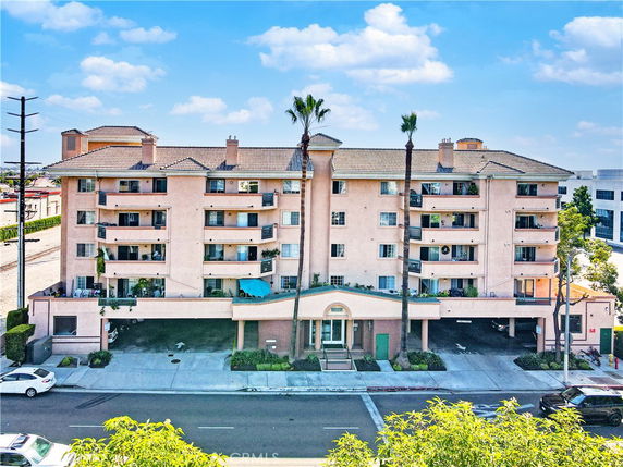 Front view of a multi-story apartment building with a covered parking area.