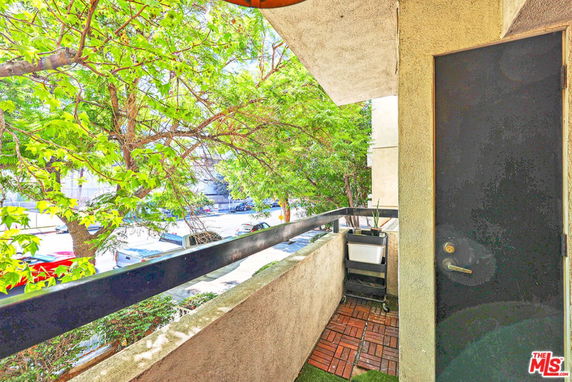Balcony view facing the street with trees and parked cars