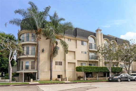 Front view of a multi-story apartment building with arched windows and balconies.