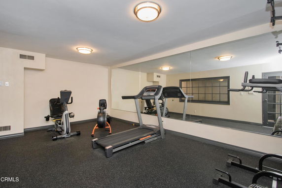 Indoor gym area with exercise equipment and wall mirrors.