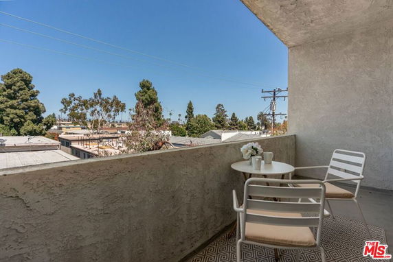 Partial view from a balcony overlooking rooftops and trees.