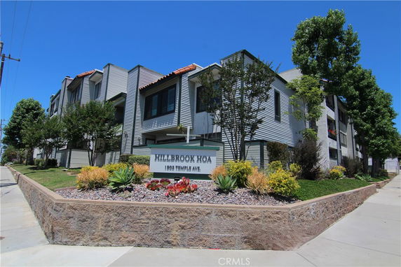 Front view of a multi-story building with a landscaped area and a sign.