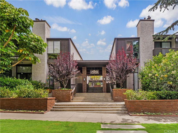 Front view of a multi-story residential building with brick accents and landscaping.