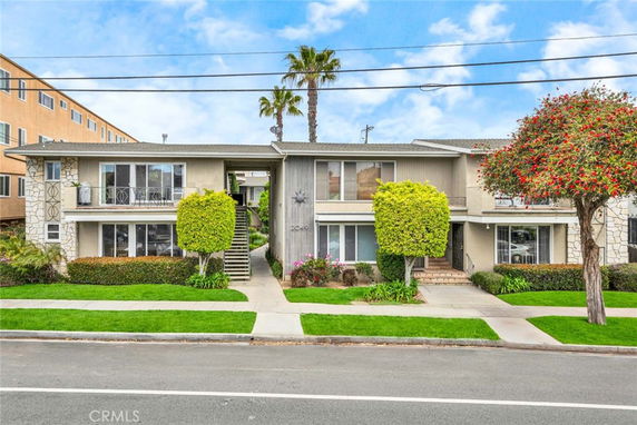 Front view of a two-story residential building with landscaped surroundings and multiple entrances.