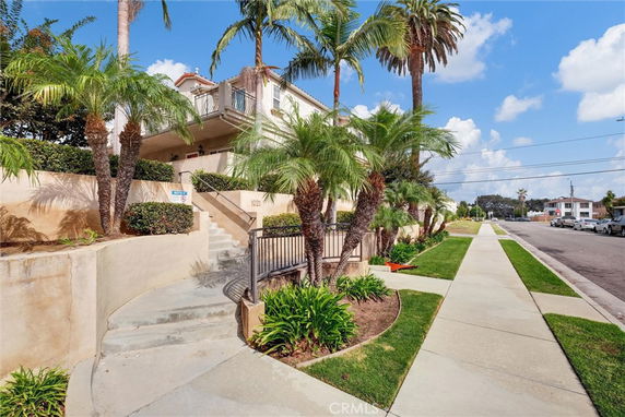 Front view of a two-story building with palm trees and an entrance staircase.