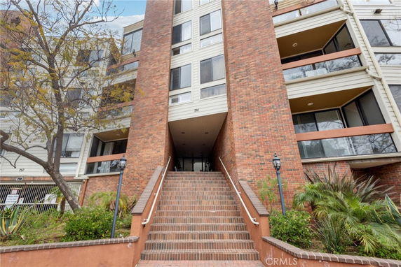 Front view of a multi-story brick apartment building with staircase entrance.