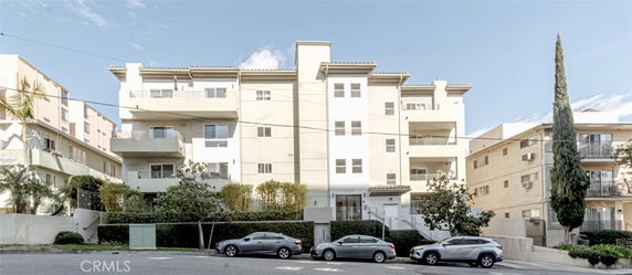 Front view of a multi-story apartment building with balconies and a flat roof.