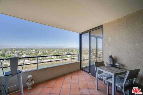 Balcony view overlooking urban landscape with mountains in the distance.