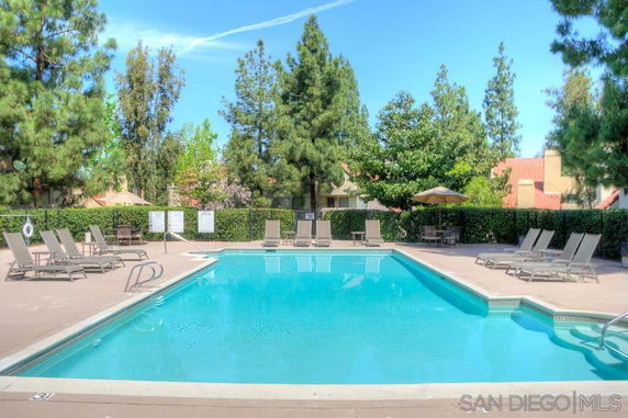 Outdoor swimming pool area with lounge chairs and umbrellas.
