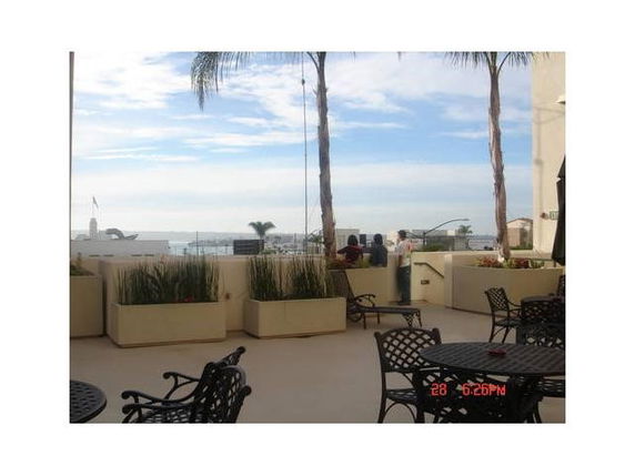 Outdoor seating area with views of distant water and palm trees.