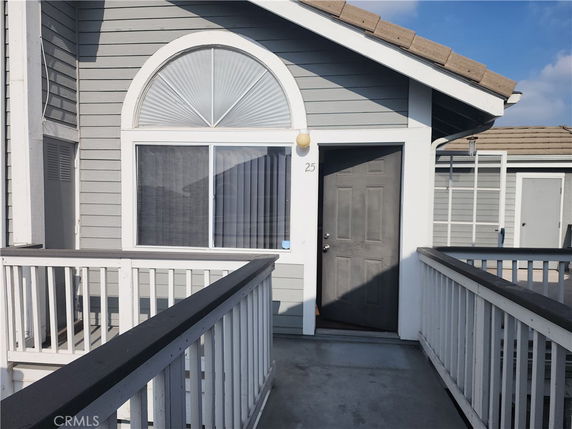 Front view of a house with a small balcony and arched window.