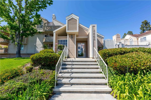 Front view of a multi-story house with a central entrance and steps leading up.